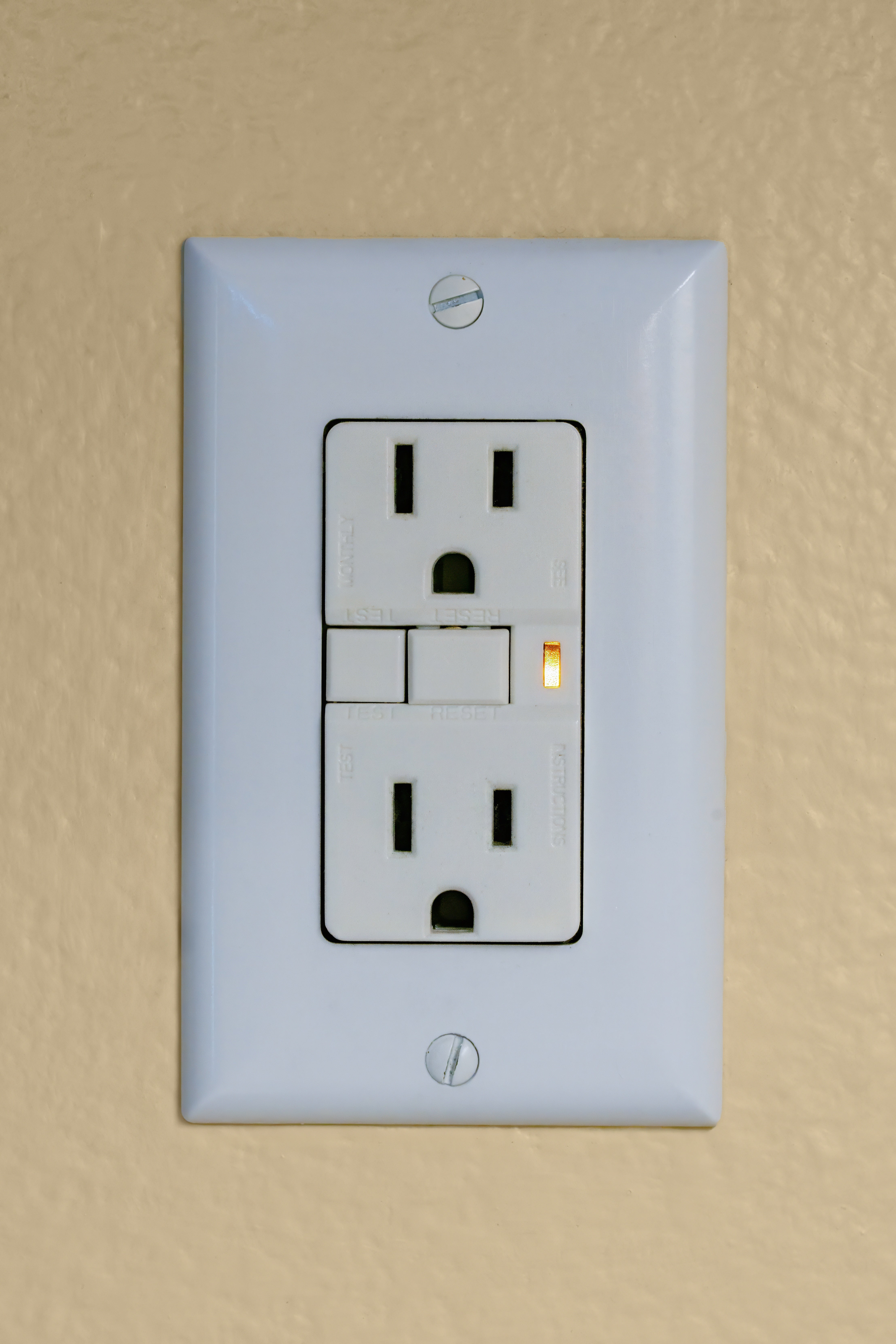 A wall outlet with two sockets and a small indicator light, mounted on a textured surface