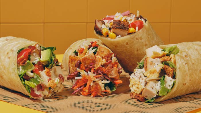 Four burritos with various fillings like chicken, vegetables, and sauces displayed on a patterned surface