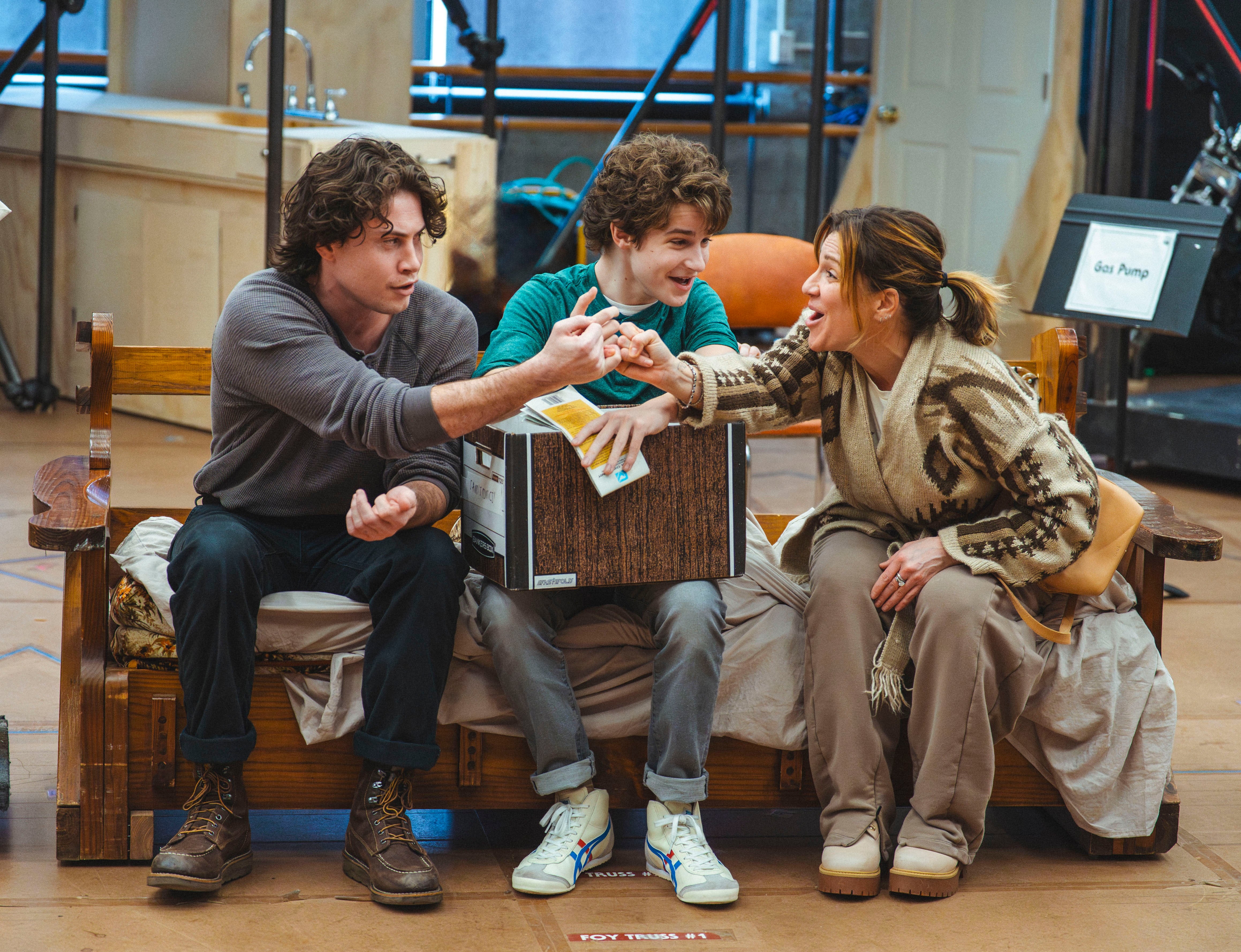Three radical beryllium connected a woody seat successful a casual setting, smiling and exchanging a playful gesture, suggesting a lively interaction