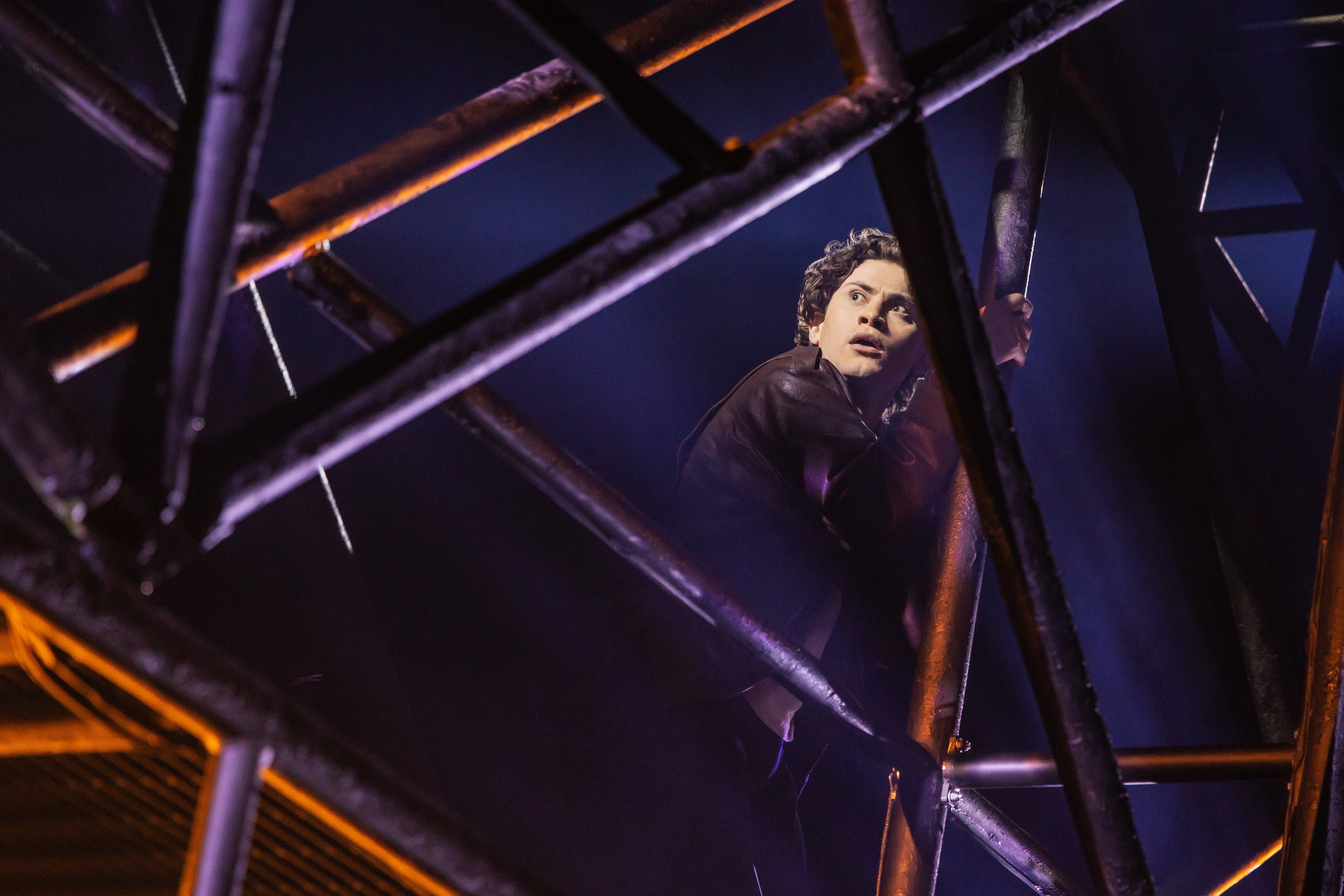 Person climbing metallic scaffolding connected signifier during a euphony performance, looking disconnected into the region with a focused expression