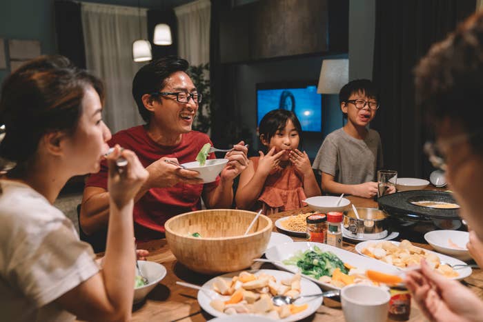 Family enjoying meal  together, seated astatine  a array  with assorted  dishes, including a ample  crockery   vessel  and respective  condiments
