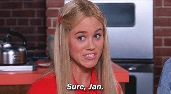 A woman with long hair, wearing a headband, gives a sarcastic expression with text overlay: "Sure, Jan." The background has a kitchen setup