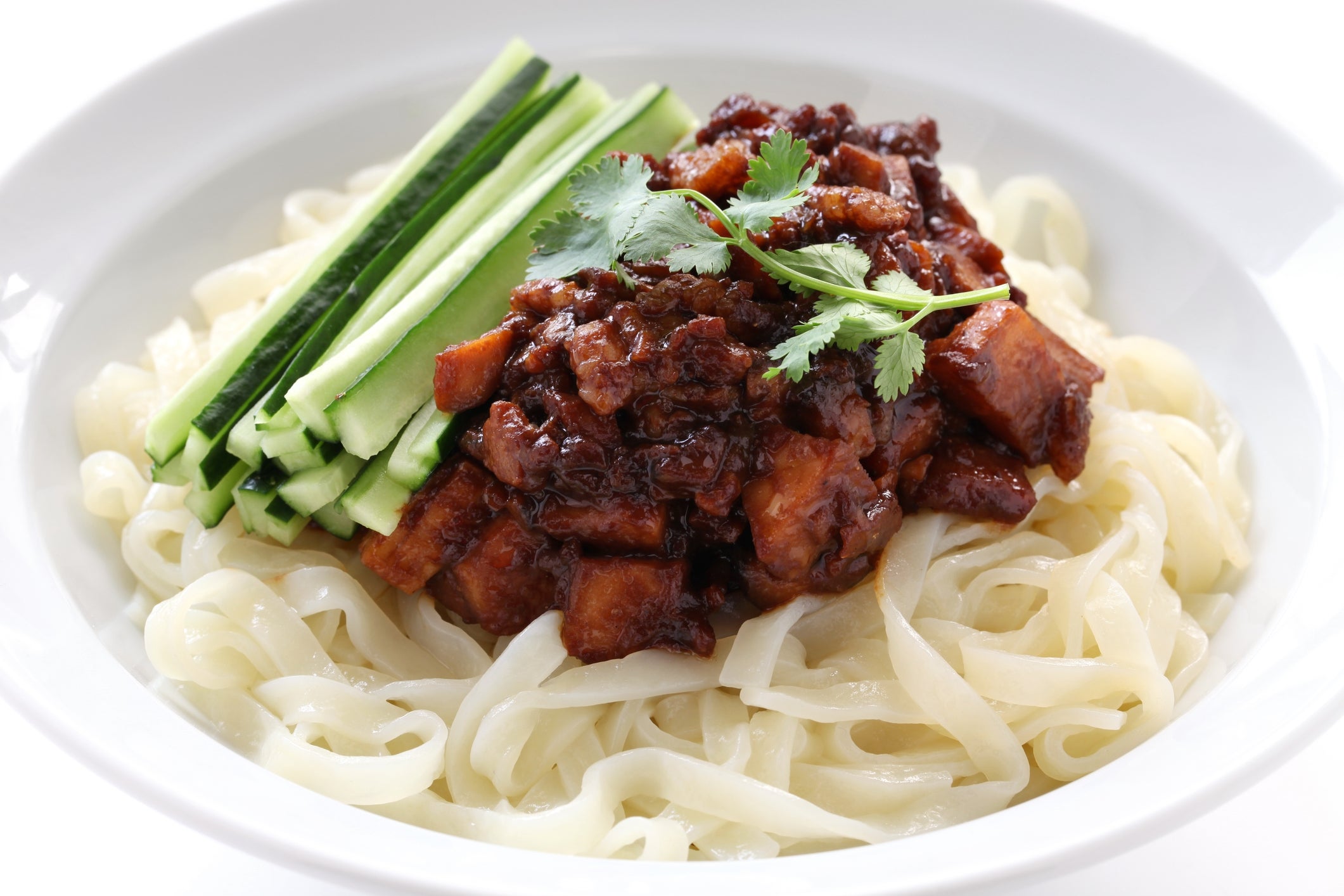 Noodles topped with diced meat, cucumber strips, and cilantro, served successful a achromatic bowl