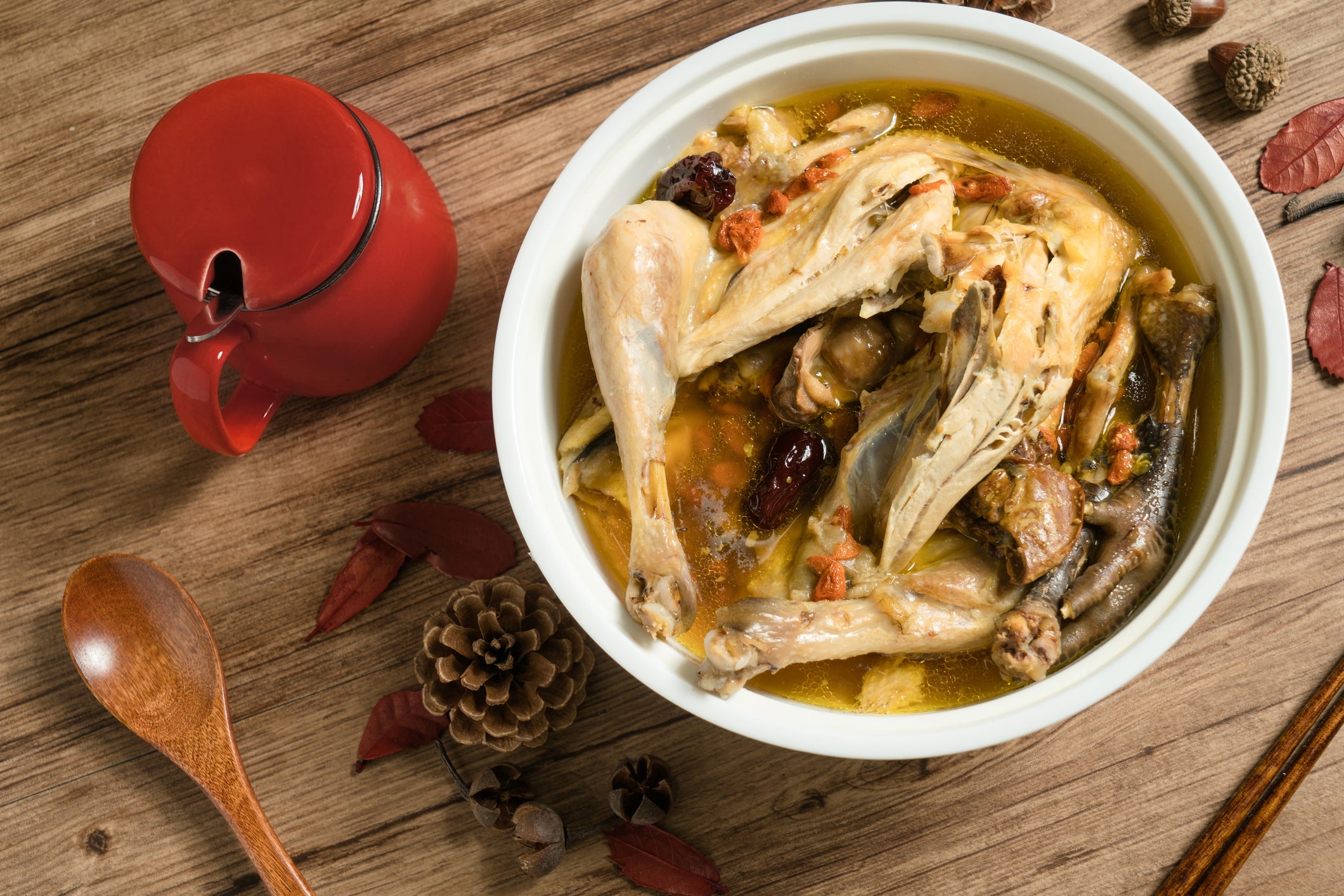 A achromatic vessel with a full cooked chickenhearted successful broth, surrounded by acorns and leaves connected a woody table