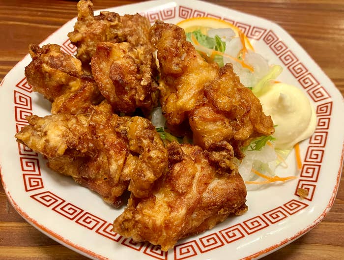 Fried chickenhearted  pieces connected  a decorative sheet  with a broadside  of shredded vegetables and creamy dipping sauce
