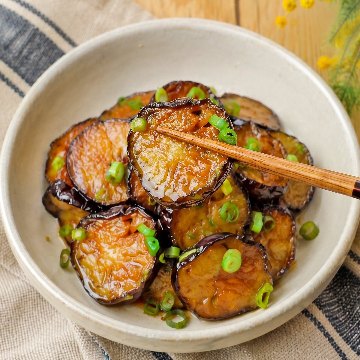 お皿に盛られた照り焼きなすの料理。上に青ねぎが散らされている。