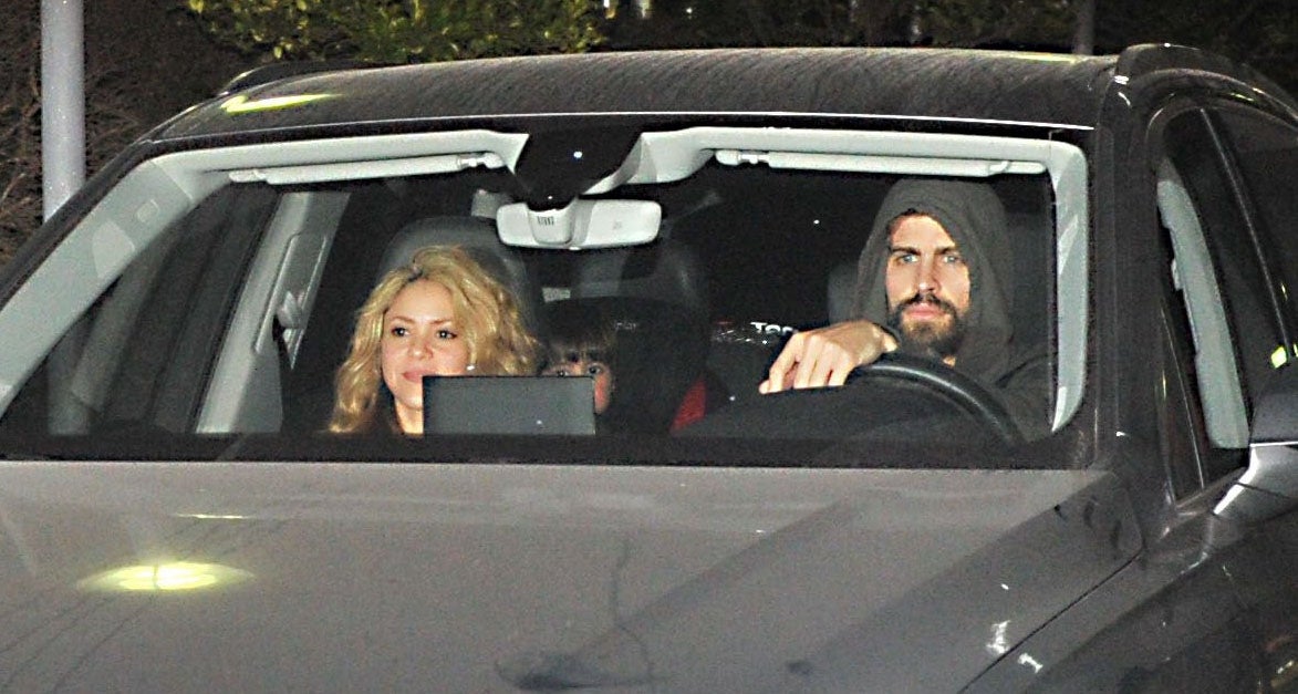 Two individuals sit in a car, one with long hair and the other wearing a hooded sweatshirt, driving at night
