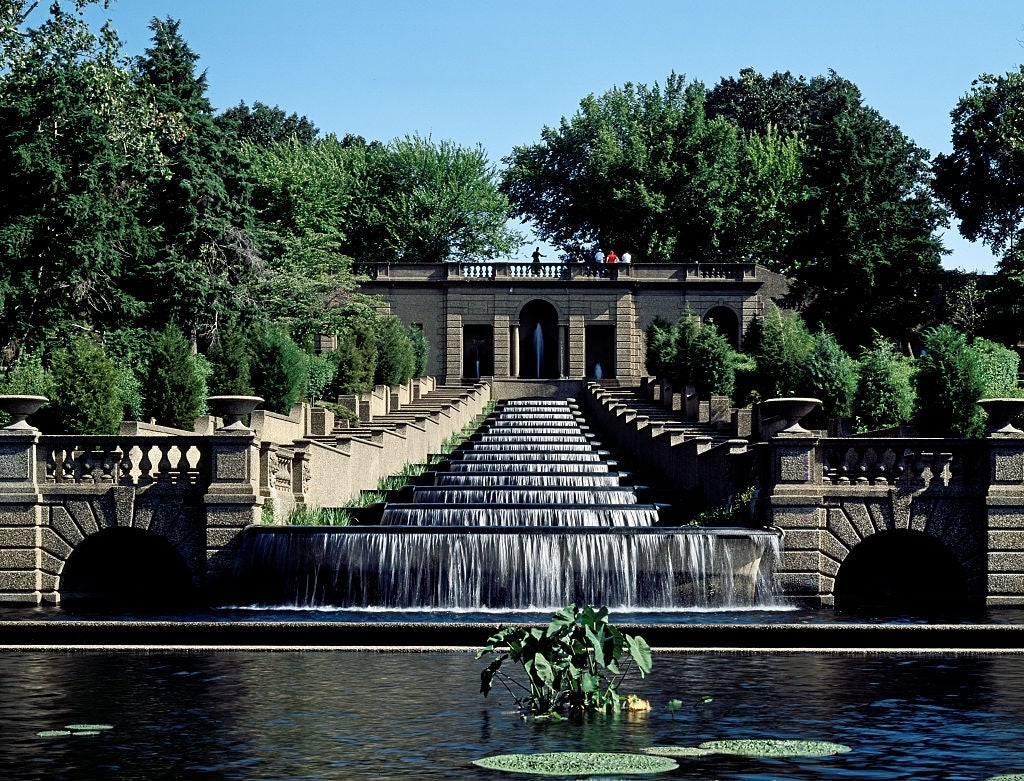 Formal garden with tiered waterfall and stone balustrades, surrounded by lush greenery