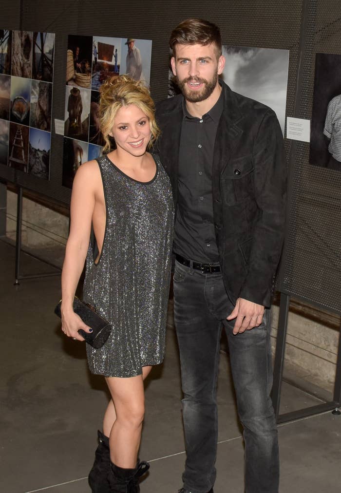 I don't know who they are. A woman in a glittery sleeveless dress and a man in a dark outfit pose at an art exhibit