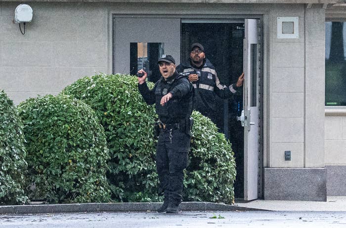 Police officers urgently exiting a building, with one holding a radio and appearing to communicate, suggesting an active or urgent situation