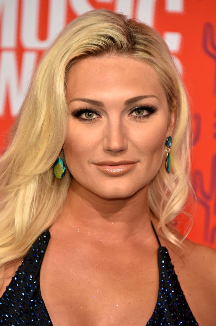Brooke Hogan on red carpet with long blonde hair, wearing a sleeveless, sparkly outfit and large earrings