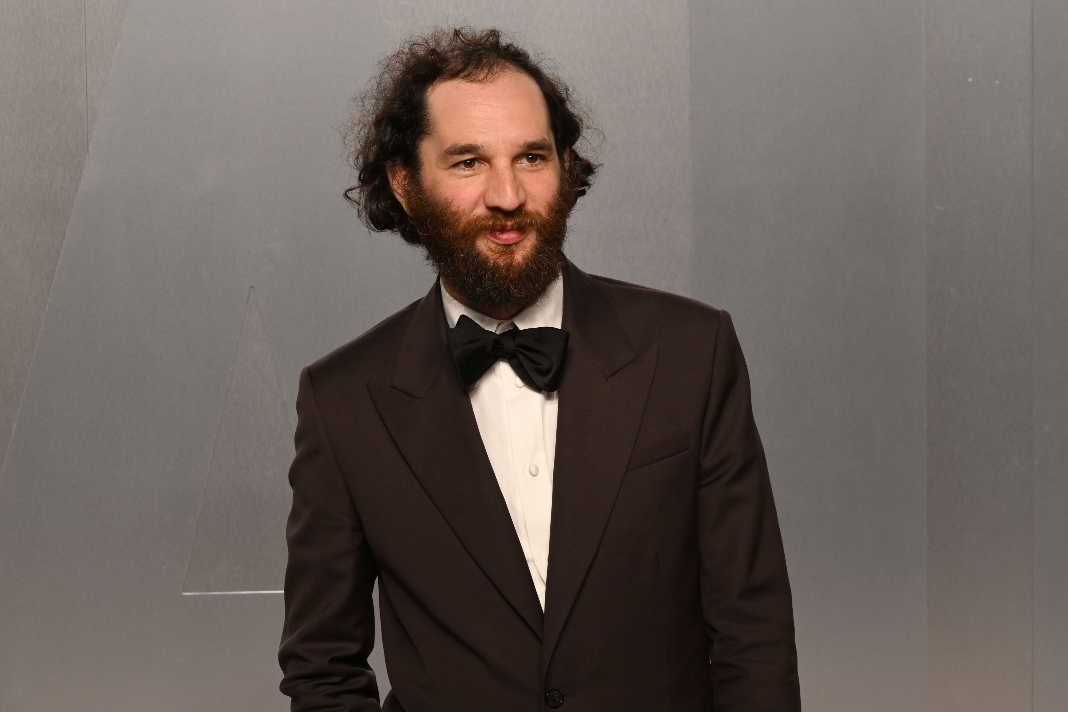 Man with a beard successful  a suit   and bow necktie  astatine  a ceremonial  event
