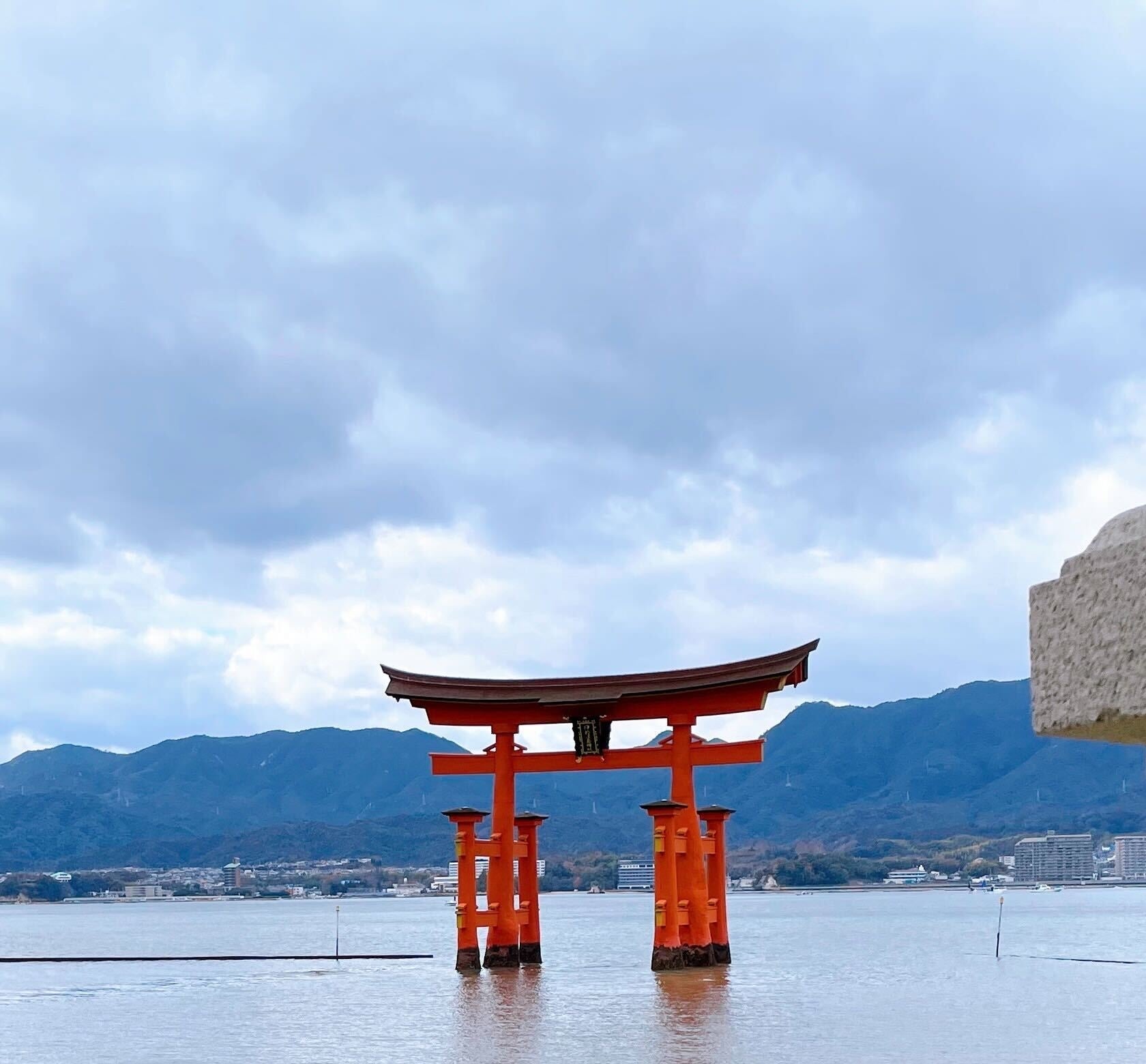 水上に立つ厳島神社の鳥居と山の風景。