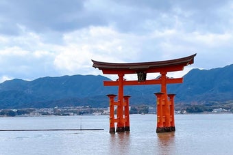 水上に立つ厳島神社の鳥居と山の風景。