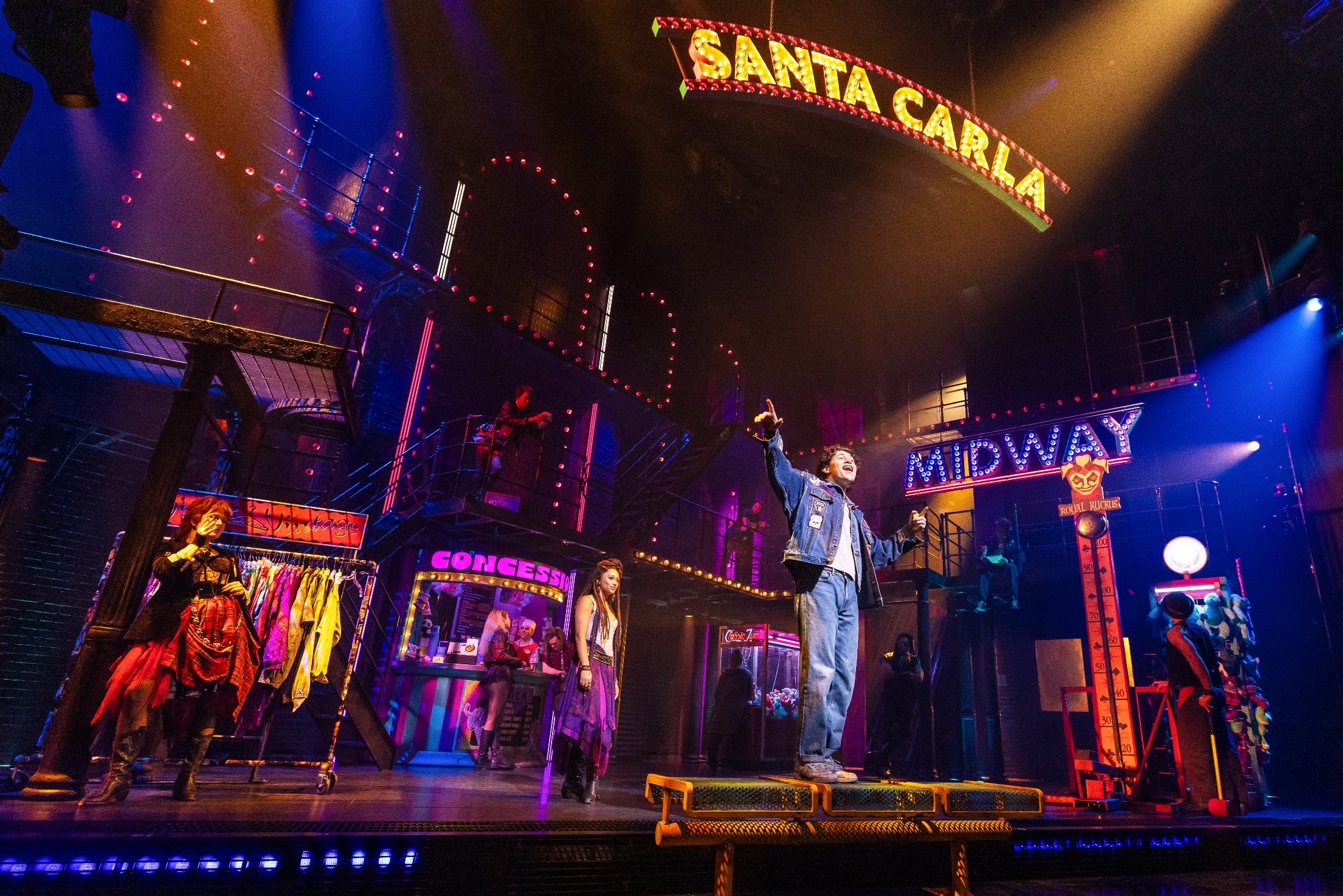 Musical theatre signifier country with actors performing nether a "Santa Carla" sign, vibrant acceptable design, including a concession country and midway lights