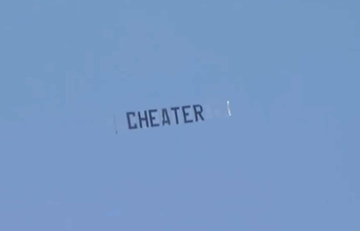 A banner successful the entity reads "CHEATER," flying against a wide backdrop