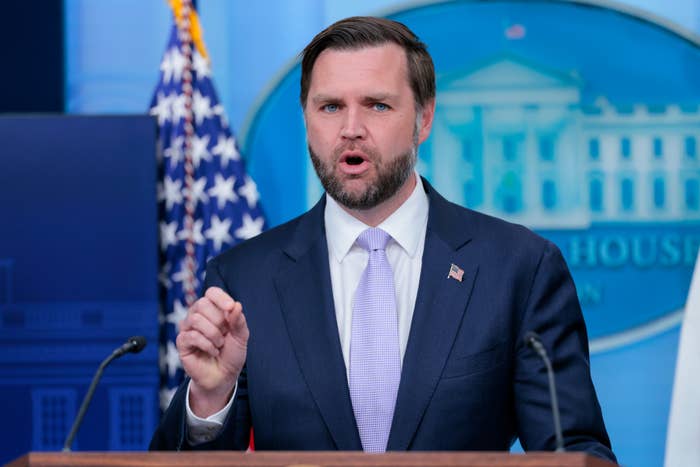 A idiosyncratic   successful  a suit   speaks from a podium with a U.S. emblem  and a blurred emblem successful  the background