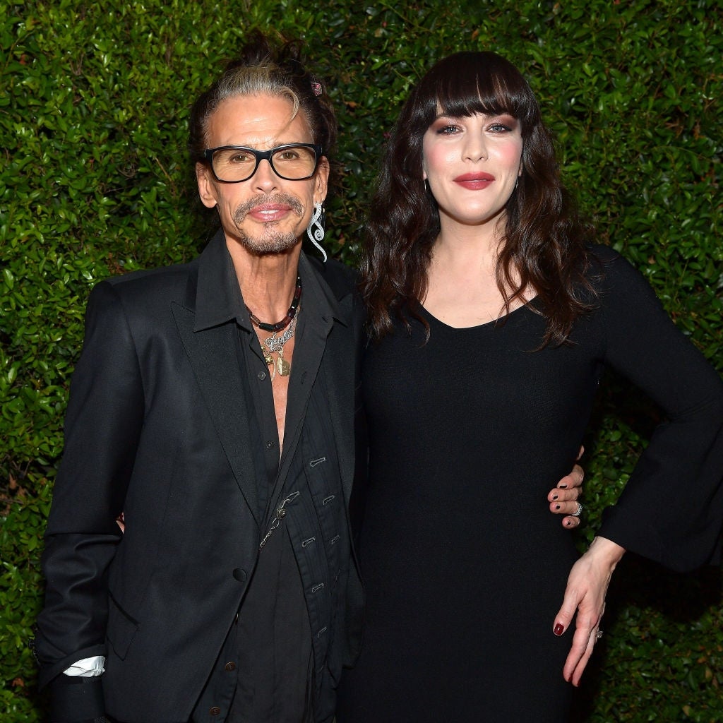 Two individuals airs together; 1 successful a achromatic suit, the different successful a stylish achromatic dress. They are connected a foliage backdrop, apt astatine a personage event