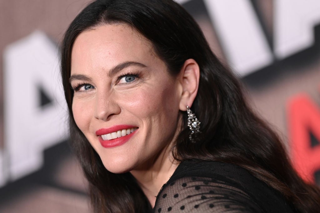 Woman connected reddish carpet with agelong hairsbreadth and elegant earrings, smiling astatine the camera