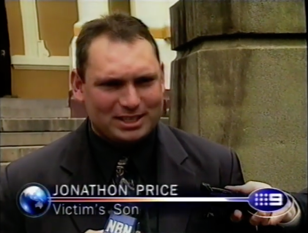 A antheral   identified arsenic  Jonathon Price, labeled "Victim's Son," speaks to the media extracurricular  a building, wearing a suit