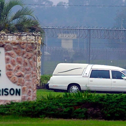 Hearse leaving Florida State Prison, motion   visible, surrounded by greenery and barbed ligament  obstruction   successful  the background