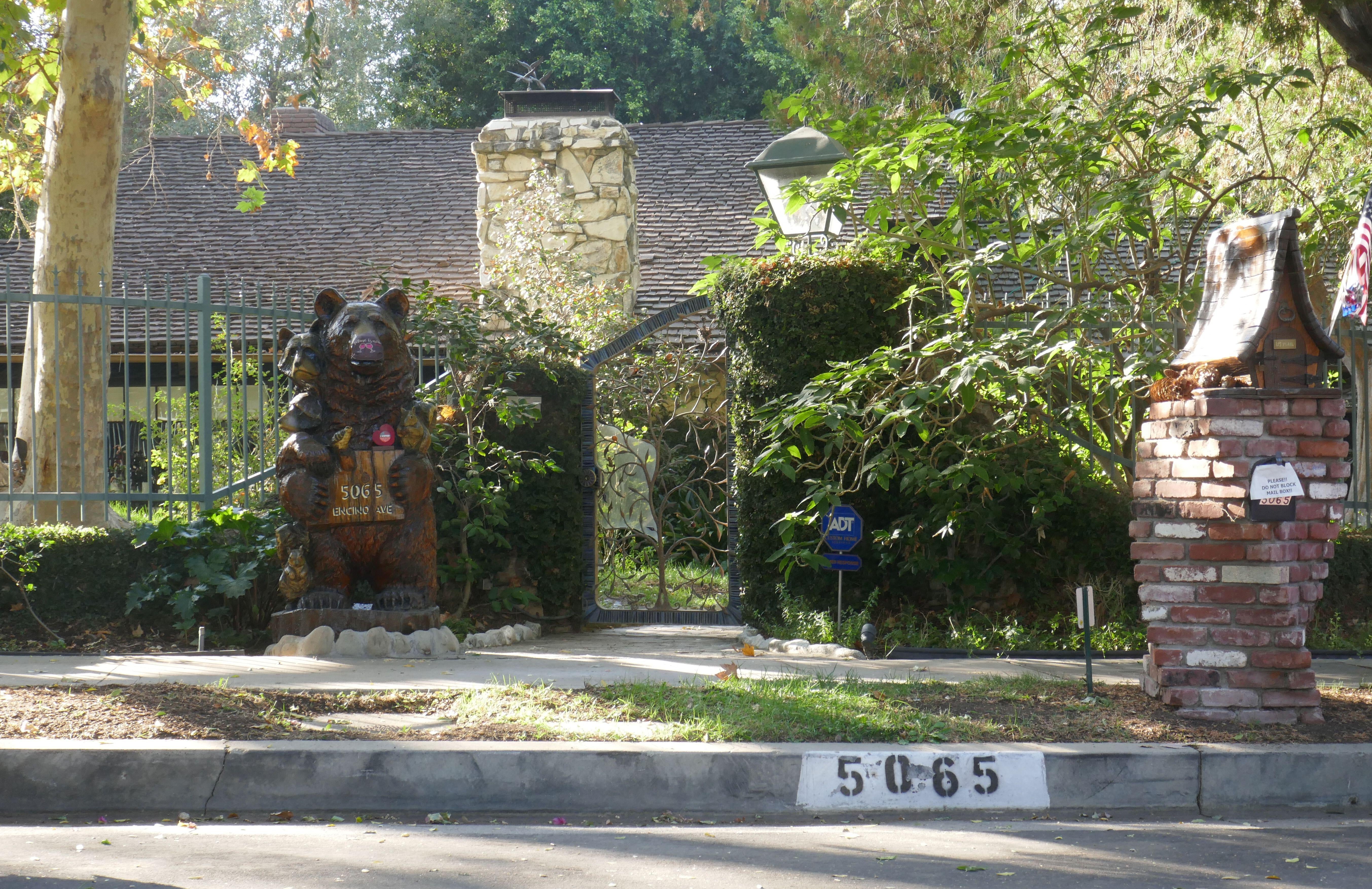 Bear statue holding cub successful  beforehand   of a chromatic  location   with trees and a mailbox nearby. House fig   5065 is disposable   connected  the curb