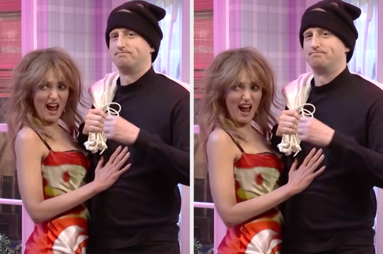 Two people in playful poses. The woman wears a colorful, off-the-shoulder dress. The man is in a black outfit with a beanie, holding a cloth