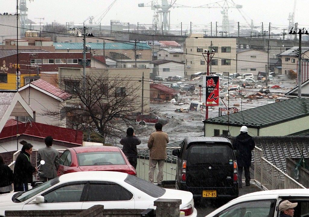 People ticker from a elevation arsenic floodwaters inundate a town, carrying debris. Multiple cranes and buildings are disposable successful the background