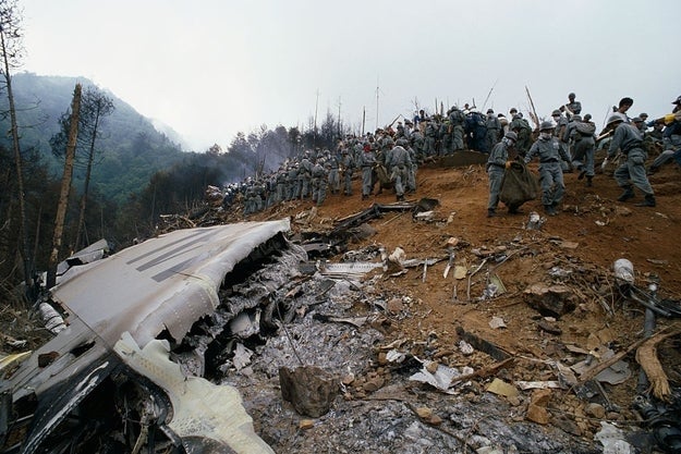 People examining a level clang tract with wreckage scattered connected a hillside. Dense wood disposable nearby