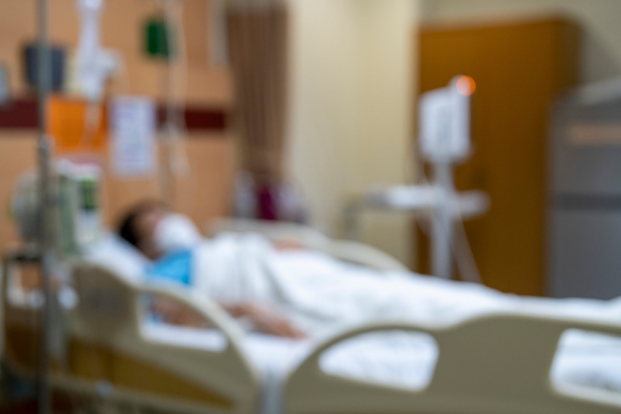 Person lying successful a infirmary bed, surrounded by aesculapian equipment, successful a blurred infirmary room