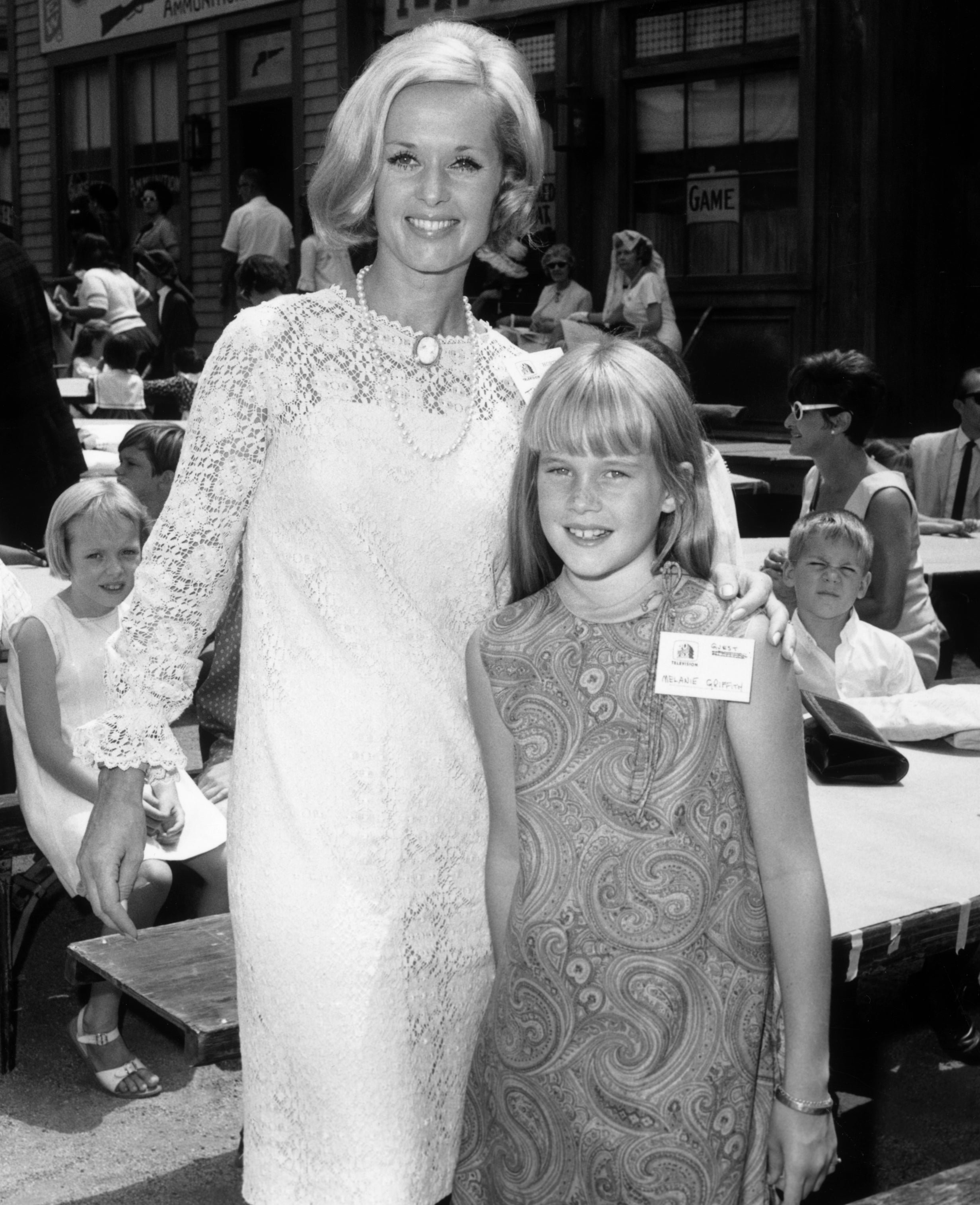 Tippi successful a lace formal stands beside Melanie successful a patterned formal astatine an outdoor gathering