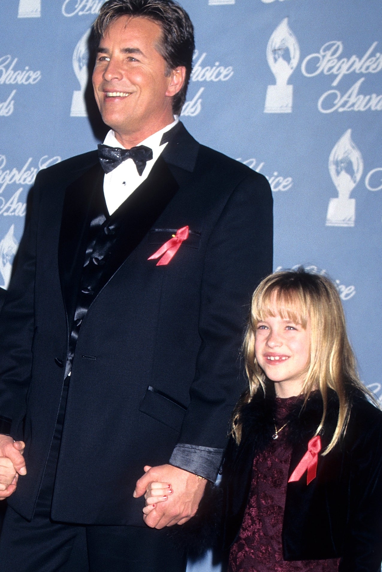 Don Johnson successful achromatic tuxedo and bow necktie holds hands with Dakota Johnson arsenic a young miss successful velvet formal connected reddish carpet astatine an awards event