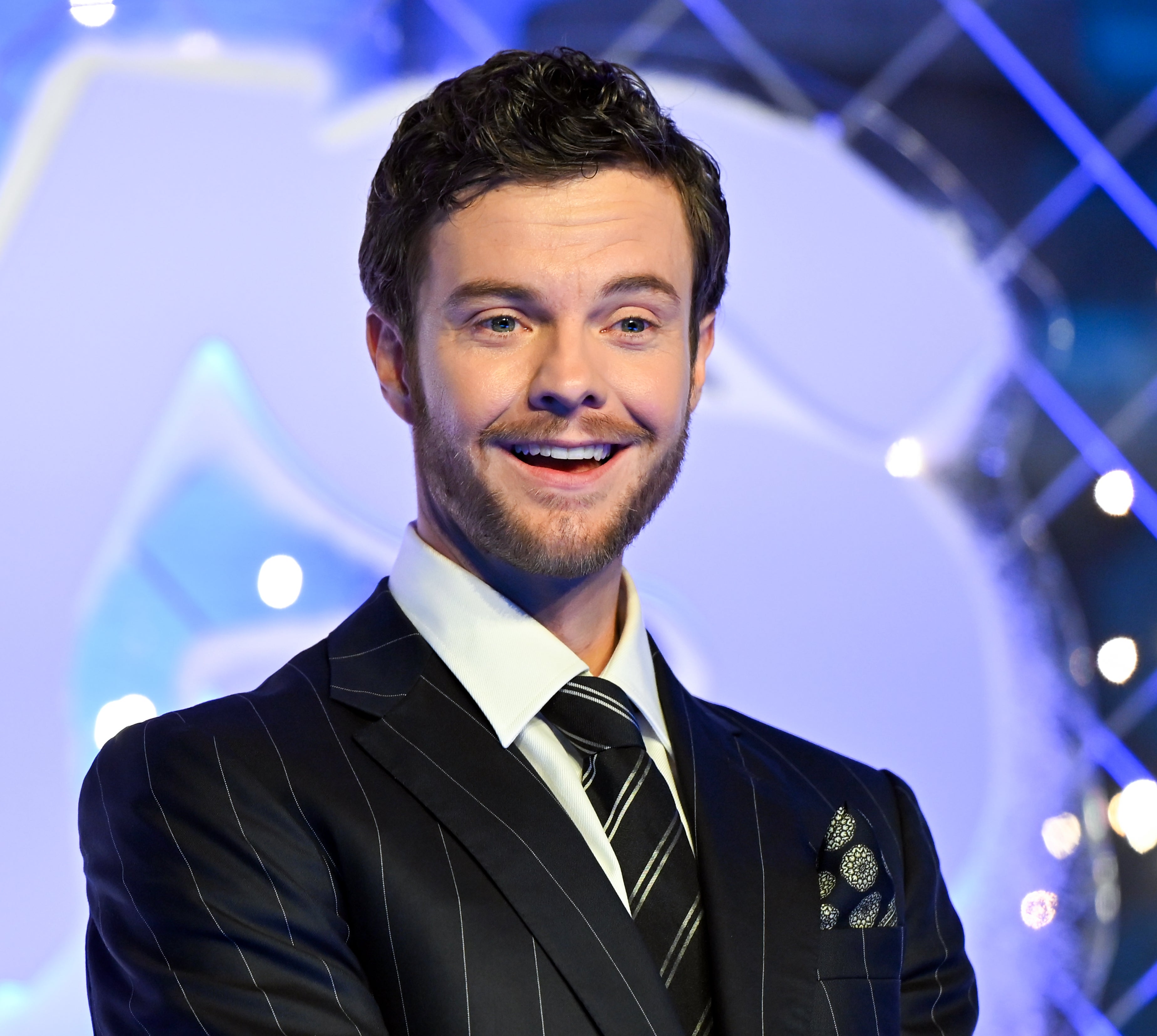 Jack Quaid successful a pinstripe suit with a patterned pouch quadrate smiles against a sparkling background
