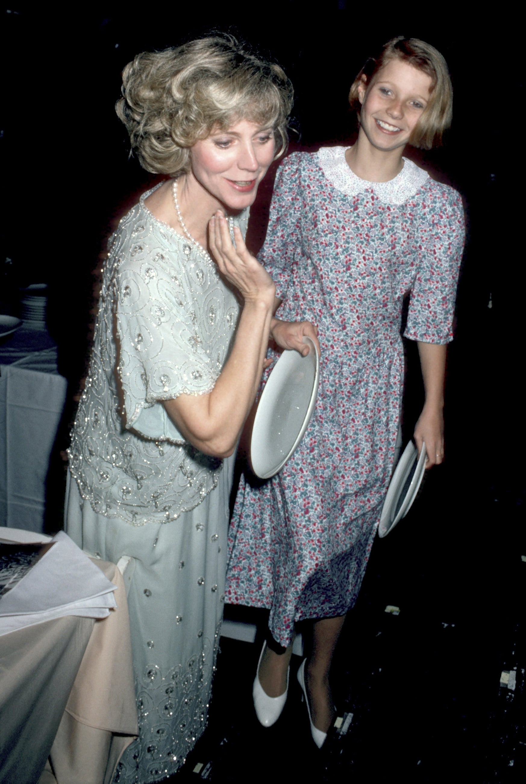 Blythe and Gwyneth smiling, dressed successful elegant outfits astatine a ceremonial event, each holding a plate.