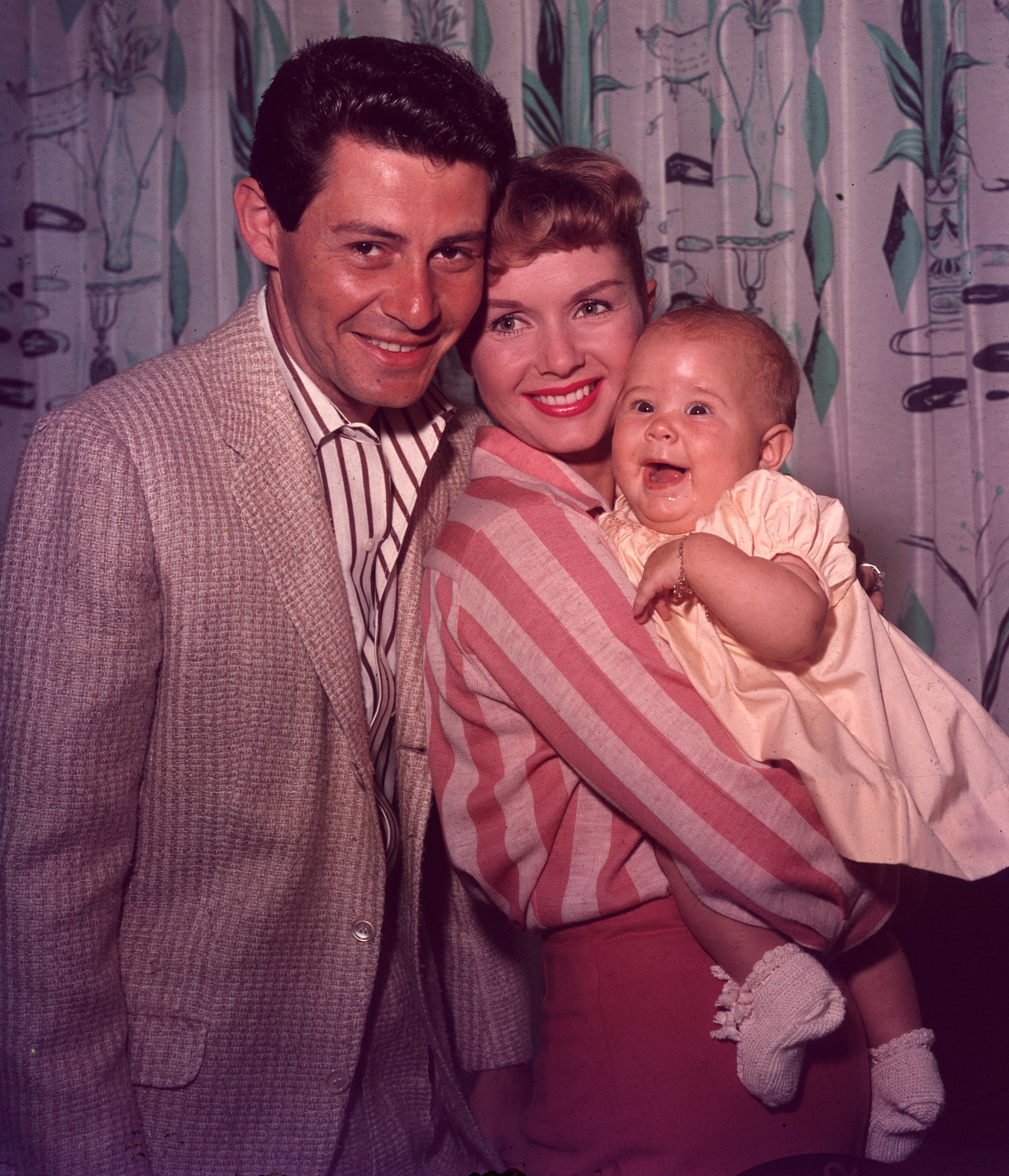 Debbie Reynolds and Eddie Fisher grin portion Debbie holds babe Carrie