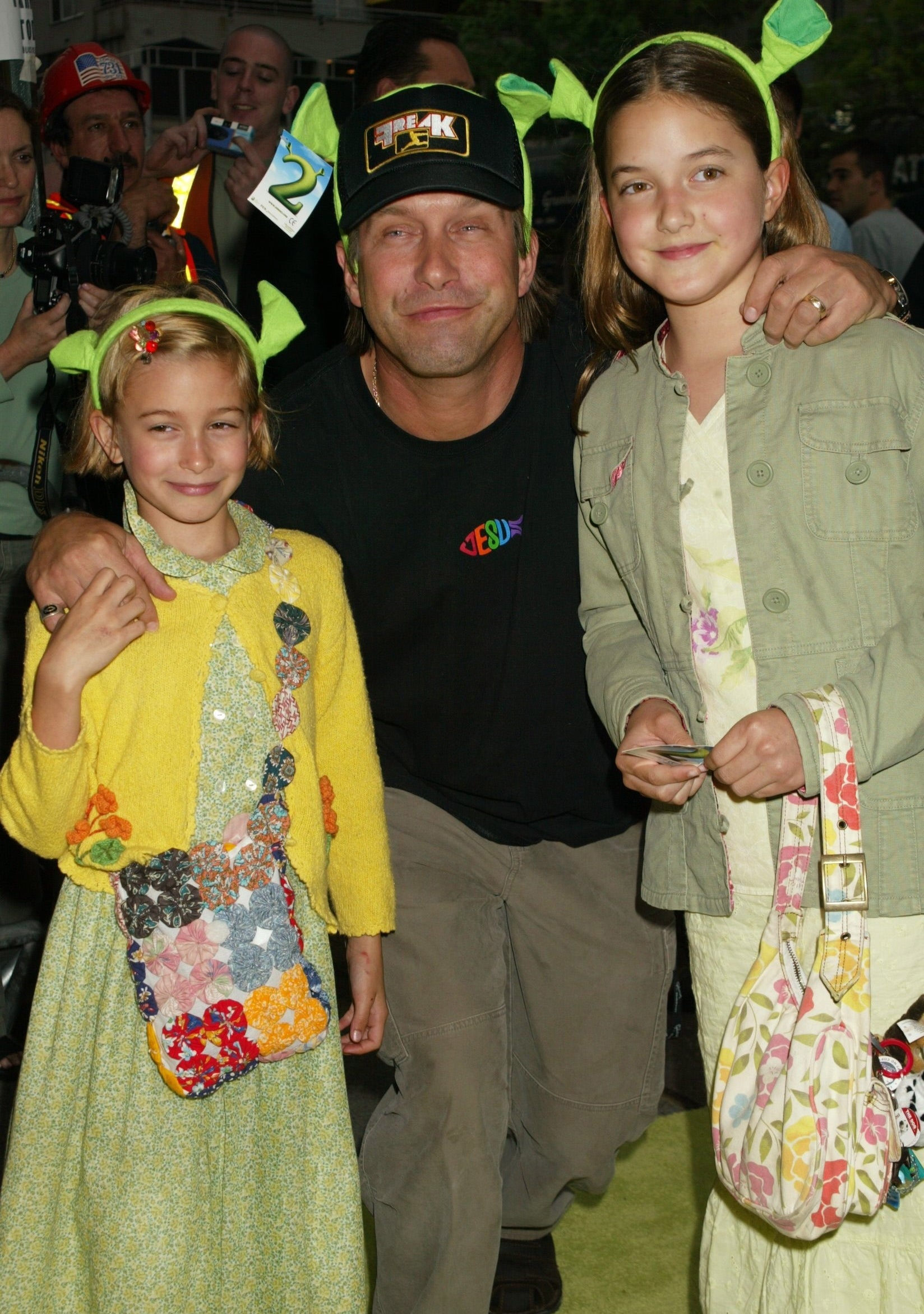 Hailey and her sister Alia deterioration playful Shrek headbands and airs with Stephen astatine an event, each smiling.
