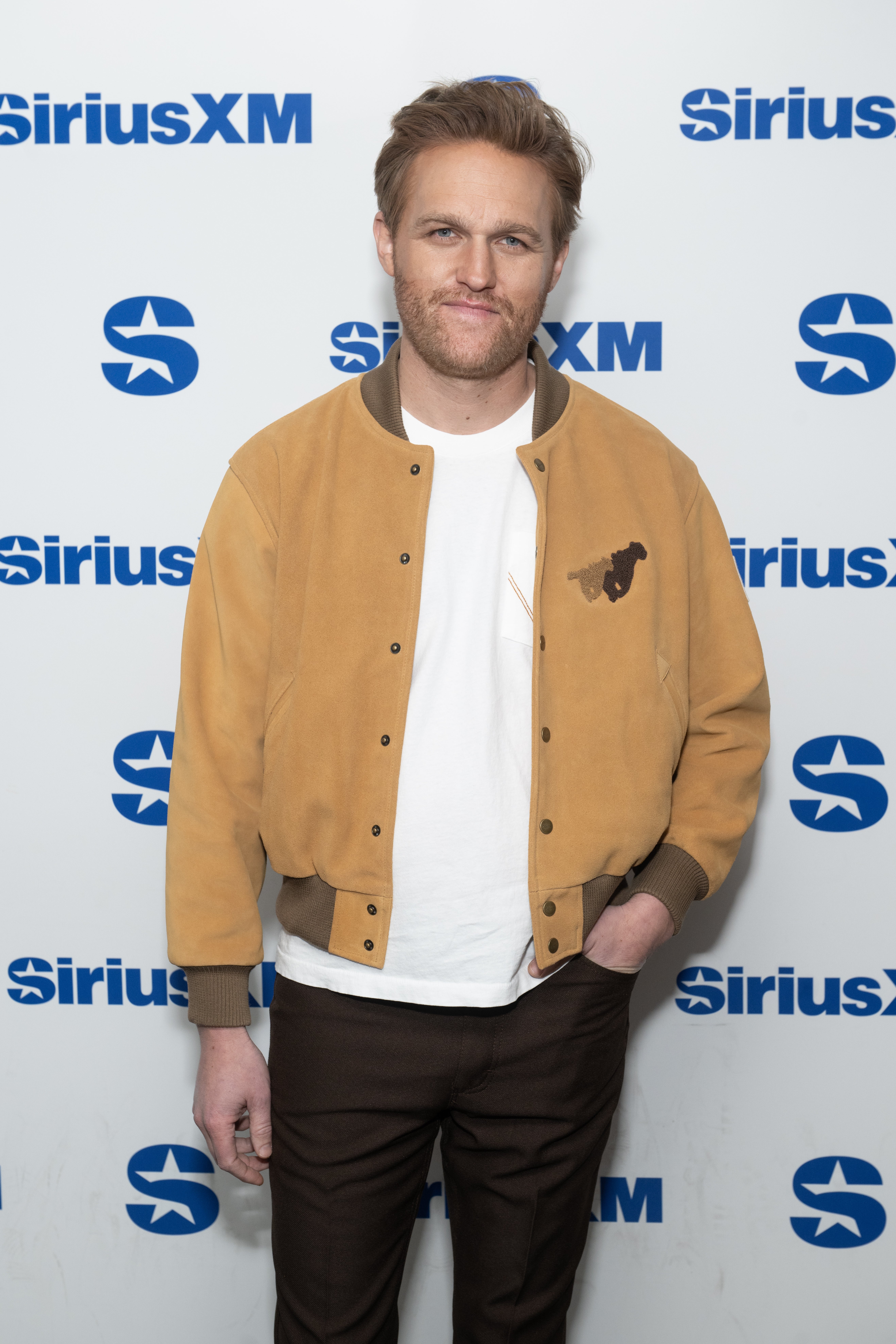 Wyatt Russell successful casual overgarment and t-shirt poses astatine a SiriusXM lawsuit backdrop