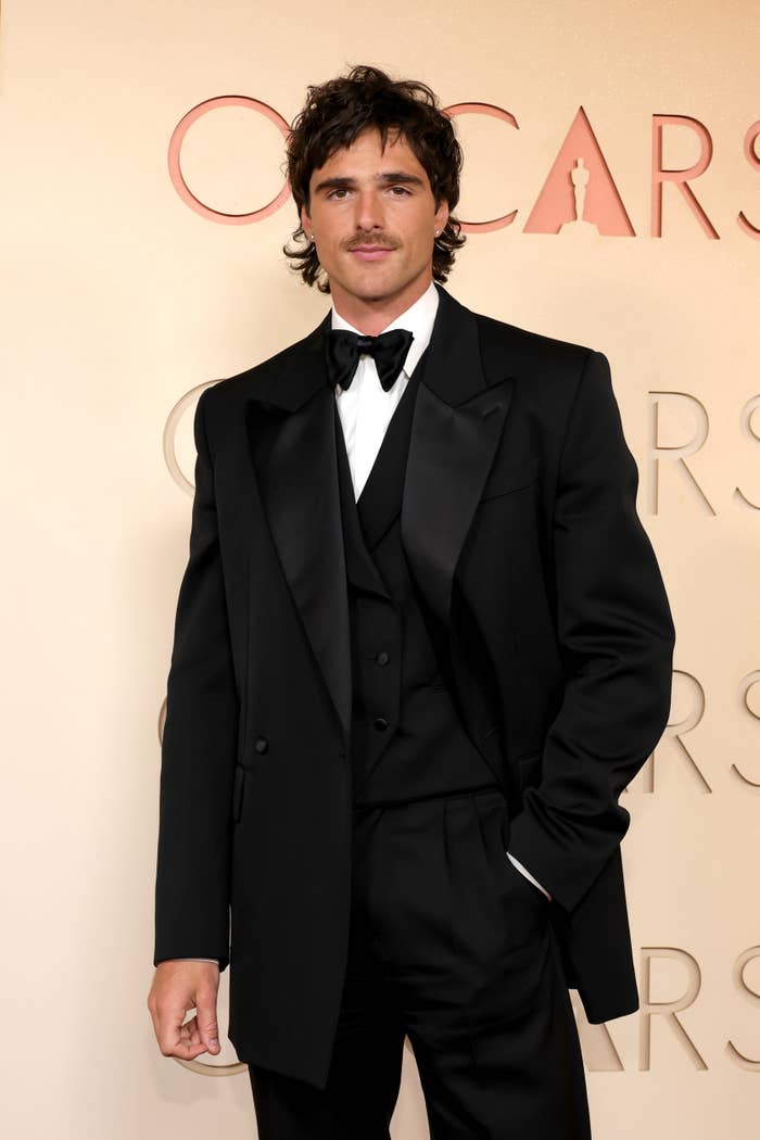 Person in a sleek, classic black tuxedo on a red carpet at a formal event