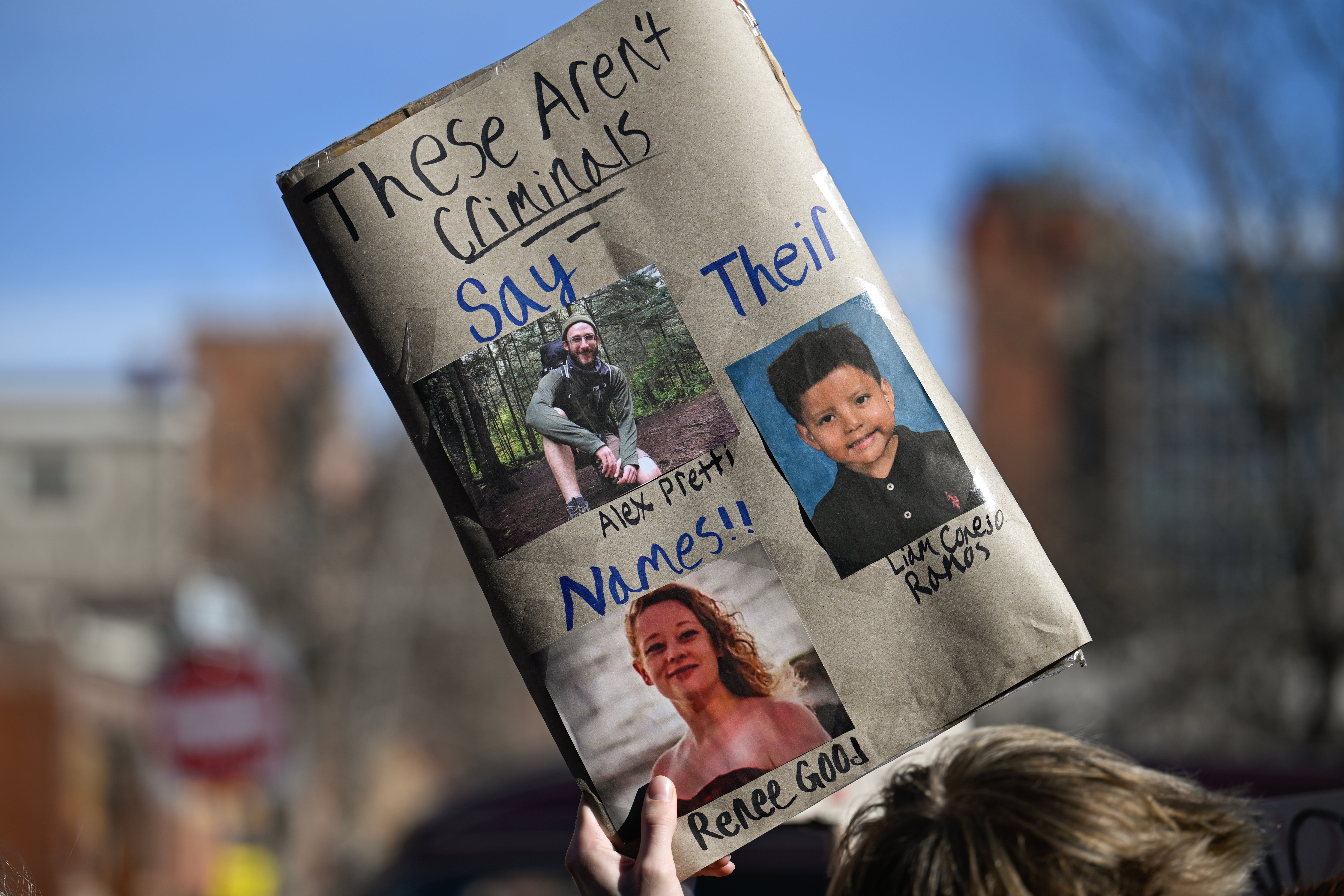 Protestskilt med bilder av tre personer merket