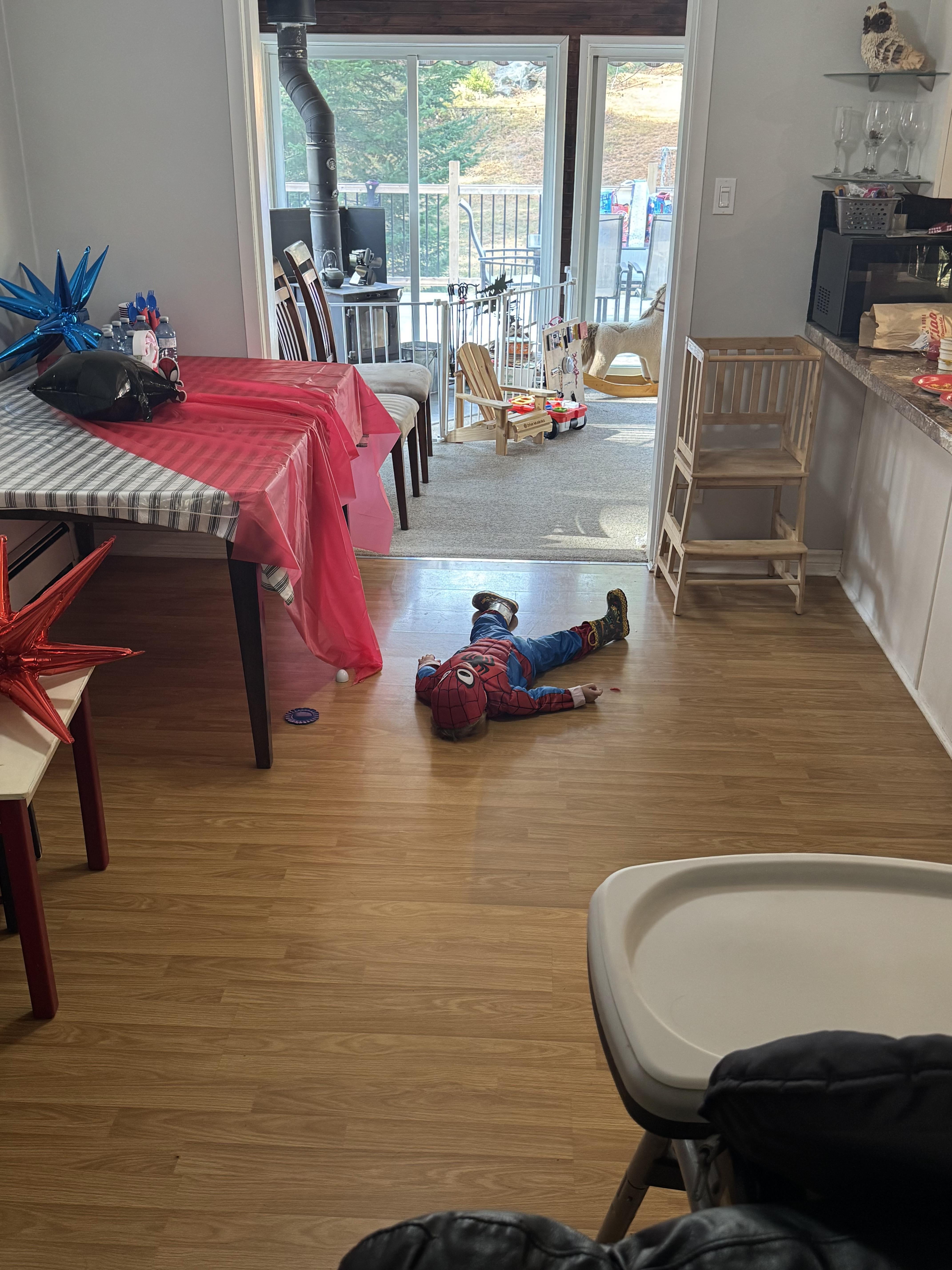 Child successful  a Spider-Man costume lies playfully face-down connected  the level  successful  a festive, decorated room