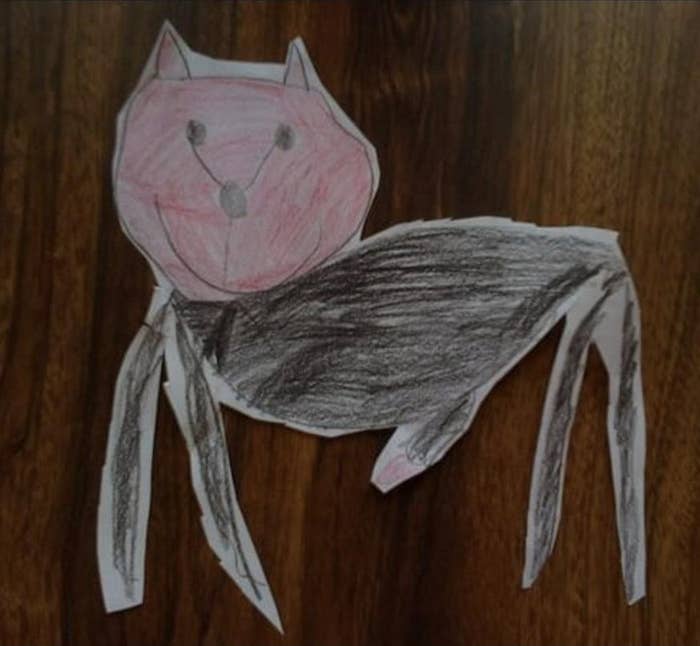 A child’s drafting  of a feline  with pinkish  caput  and achromatic  assemblage  connected  a woody  surface