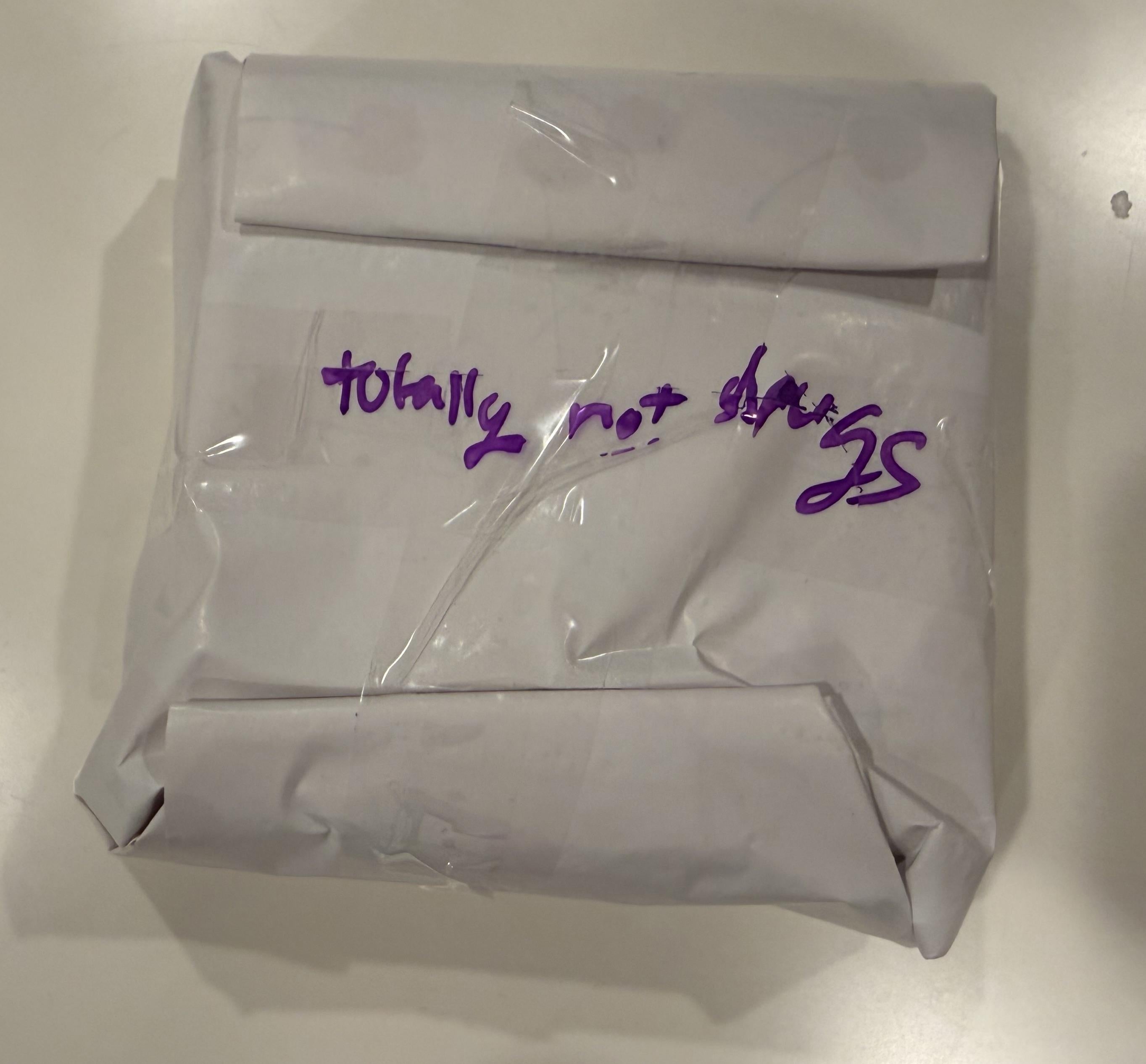 A bundle  wrapped successful  insubstantial  with handwritten substance   stating, "totally not drugs."