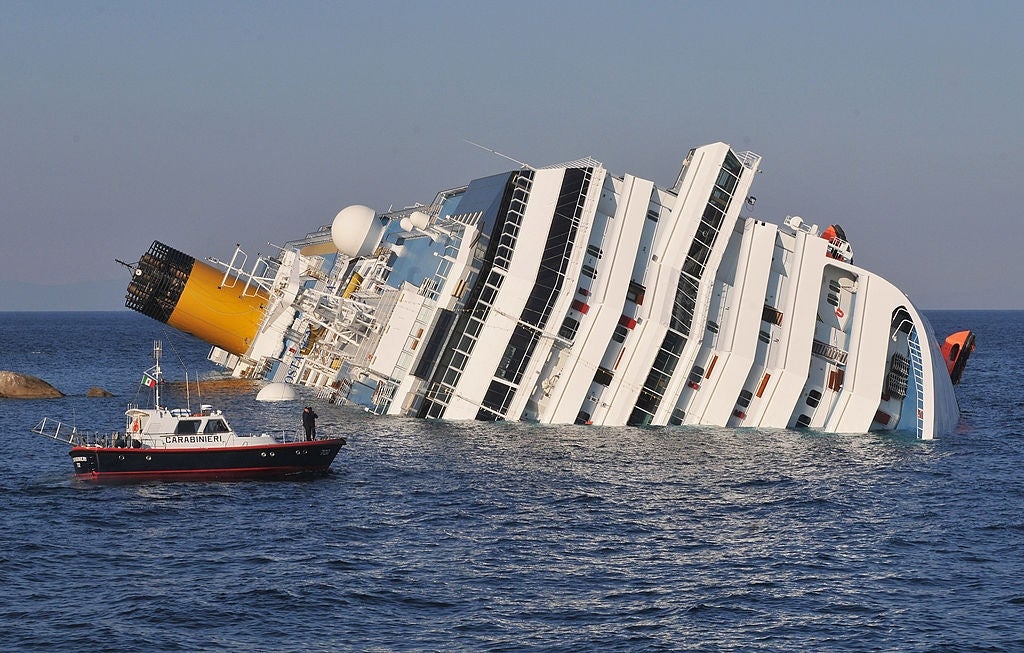 A partially submerged cruise vessel tilts successful the oversea adjacent a tiny seashore defender boat