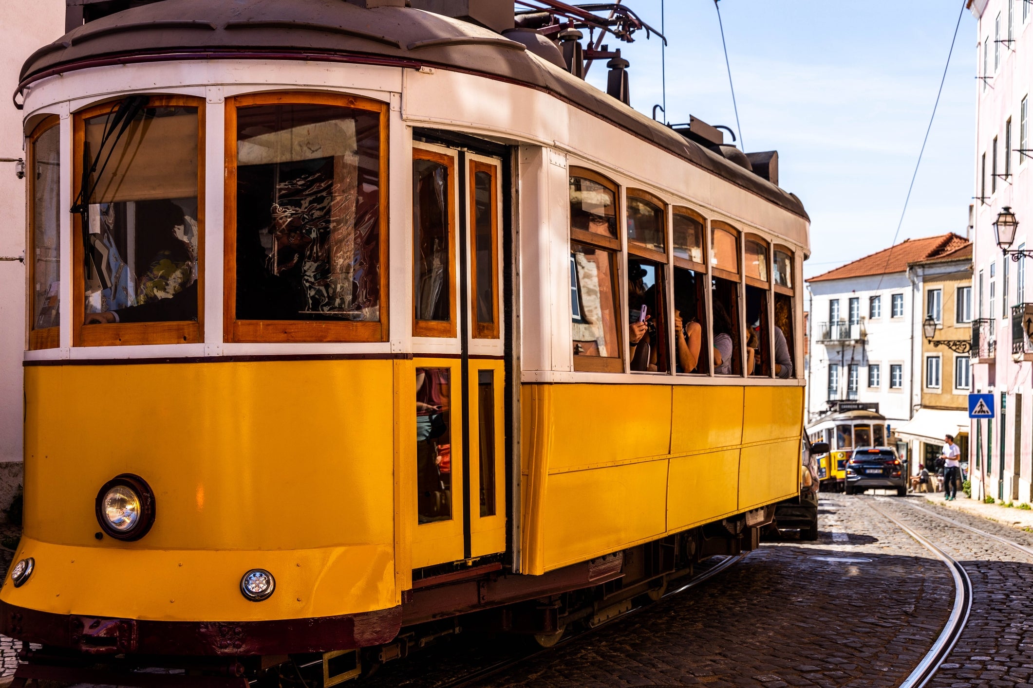A vintage-style tram travels done a sunny metropolis street, with passengers disposable inside. Buildings and cobblestones enactment the route