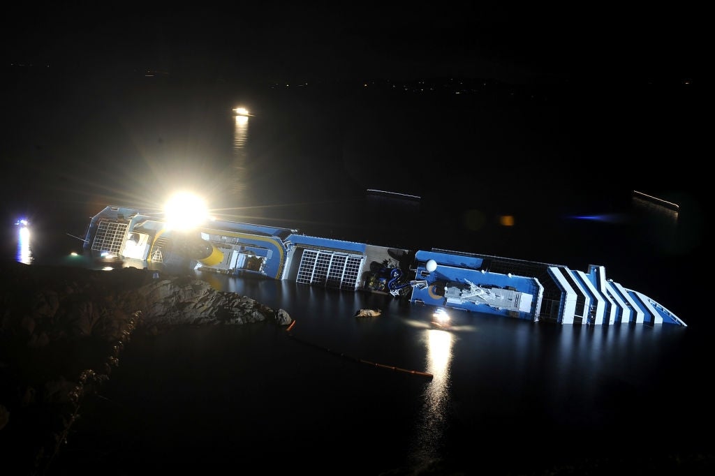 Partially submerged cruise vessel tilting connected its broadside astatine night, with agleam lights illuminating the scene