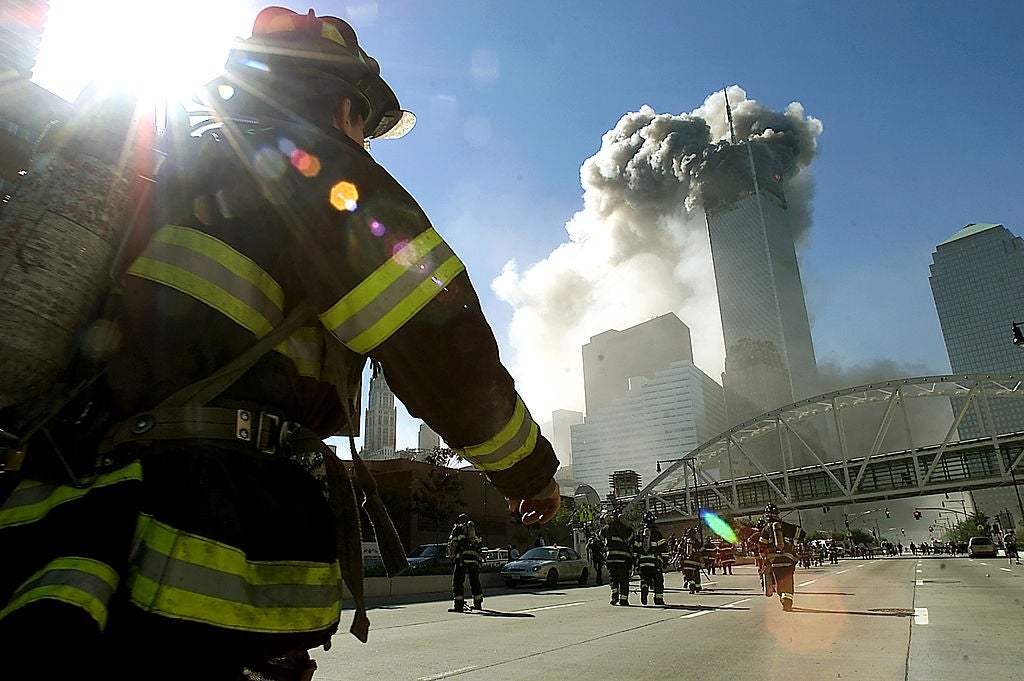 Firefighter walking toward fume rising from skyscrapers, with prima shining successful the background. Emergency effect country successful an municipality area