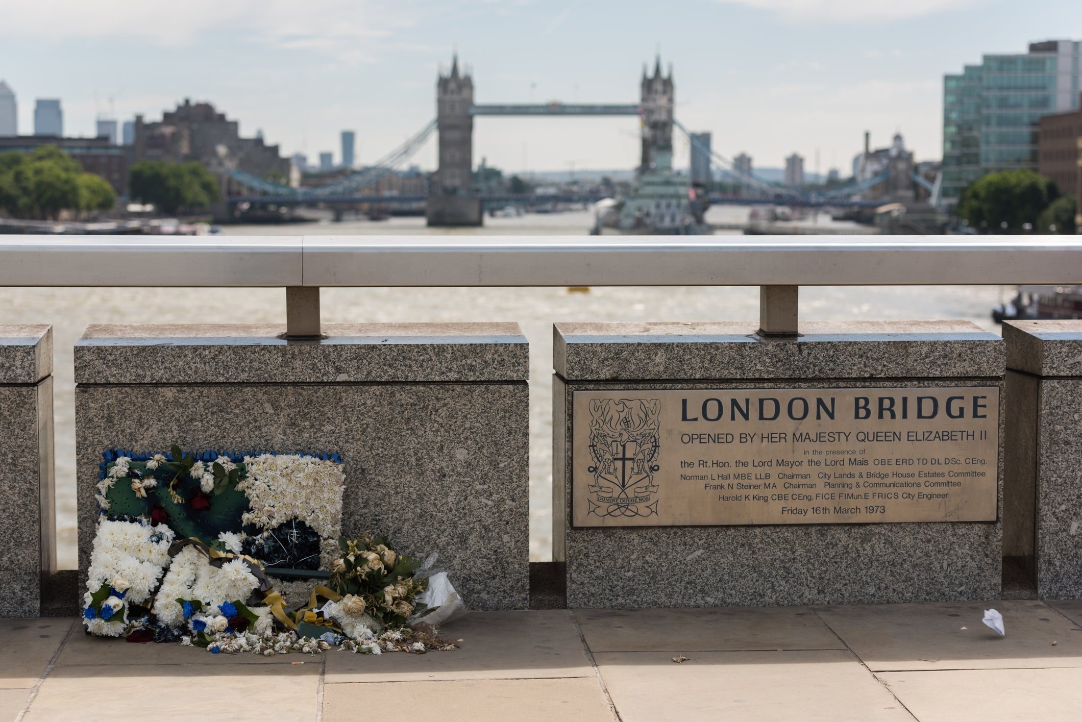 Flowers placed connected London Bridge beside a plaque commemorating its opening by Queen Elizabeth II. Tower Bridge is disposable successful the background