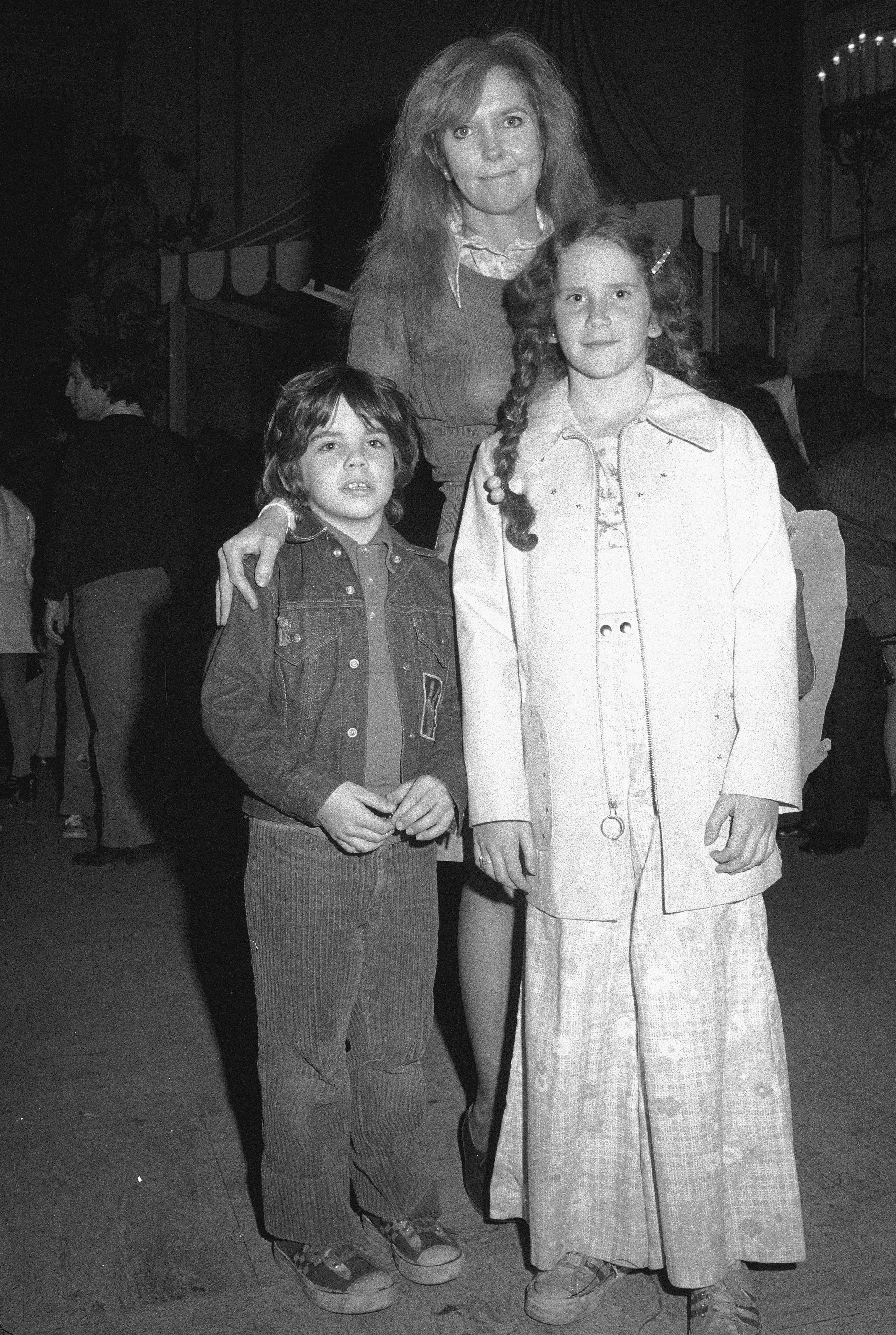 Anne stands with her 2 children successful a candid pose.