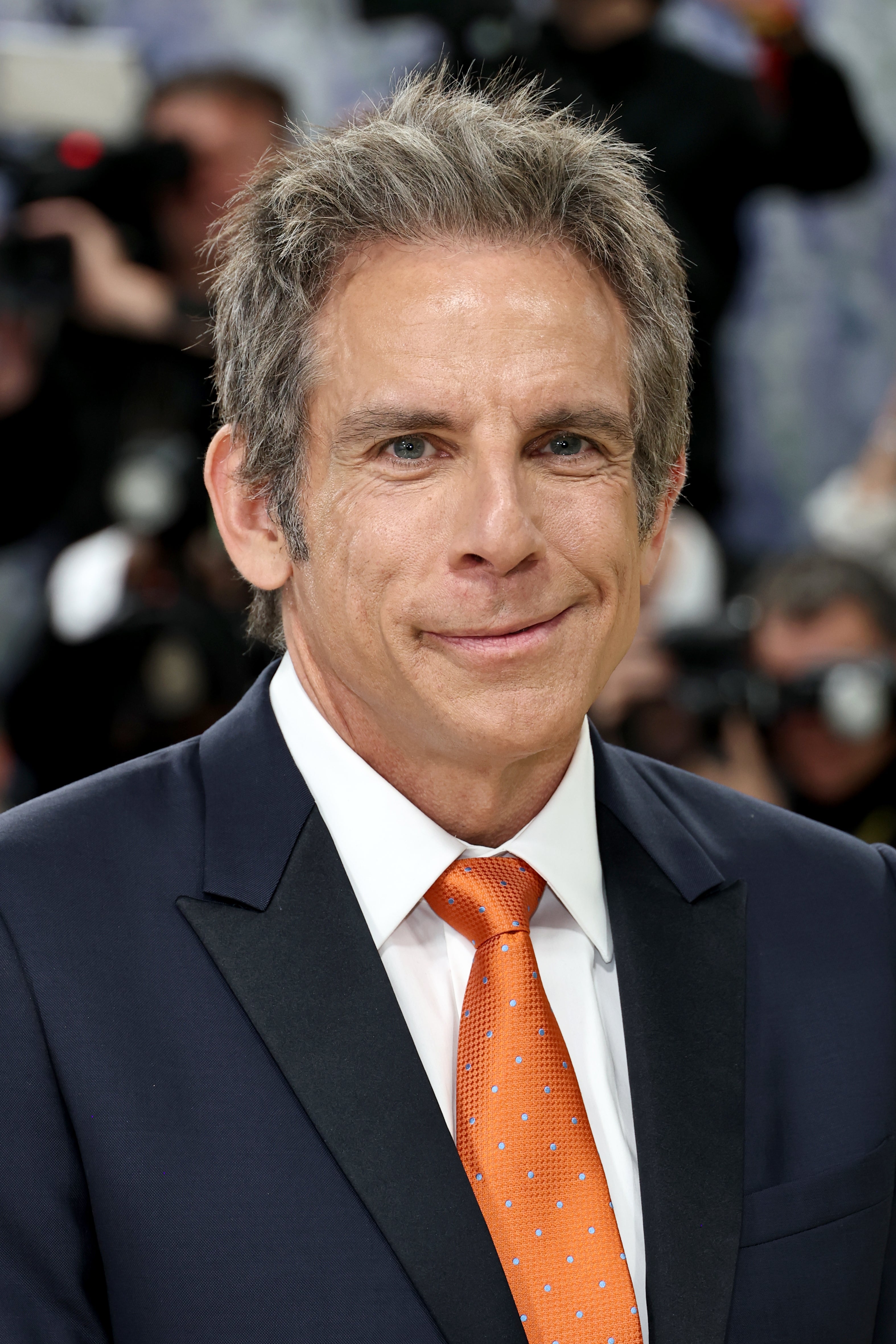 Ben Stiller successful suit with orangish polka dot necktie astatine an event, photographers successful the background