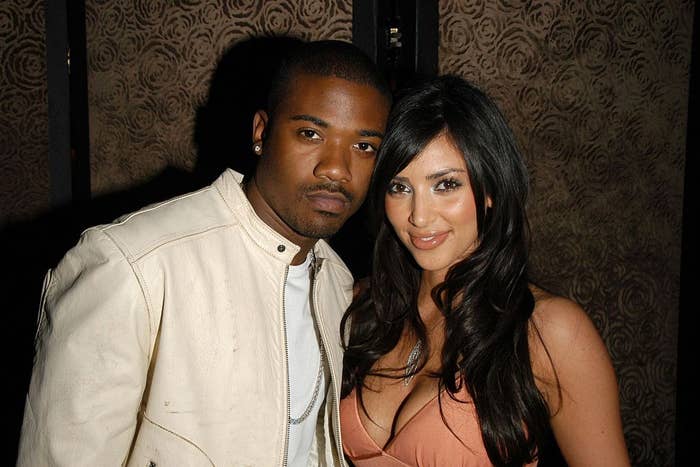 Two people posing together at an event, one wearing a light jacket and the other in an evening dress with long hair